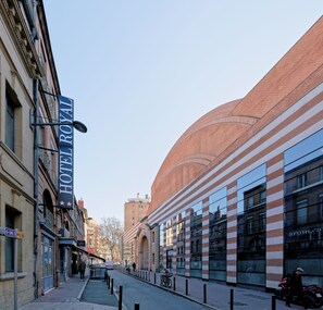 A street view with a hotel named "HOTEL ROYAL" on the left, a modern building with reflective windows on the right, and a clear sky. - Hostel Toulouse Wilson (Toulouse)