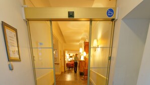 A hotel entrance with a blue carpet reading "ROYAL WILSON" and a glass door leading to a hallway. - Hostel Toulouse Wilson (Toulouse)