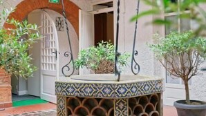 A courtyard with a decorative fountain, potted plants, and a tiled floor. - Hostel Toulouse Wilson (Toulouse)