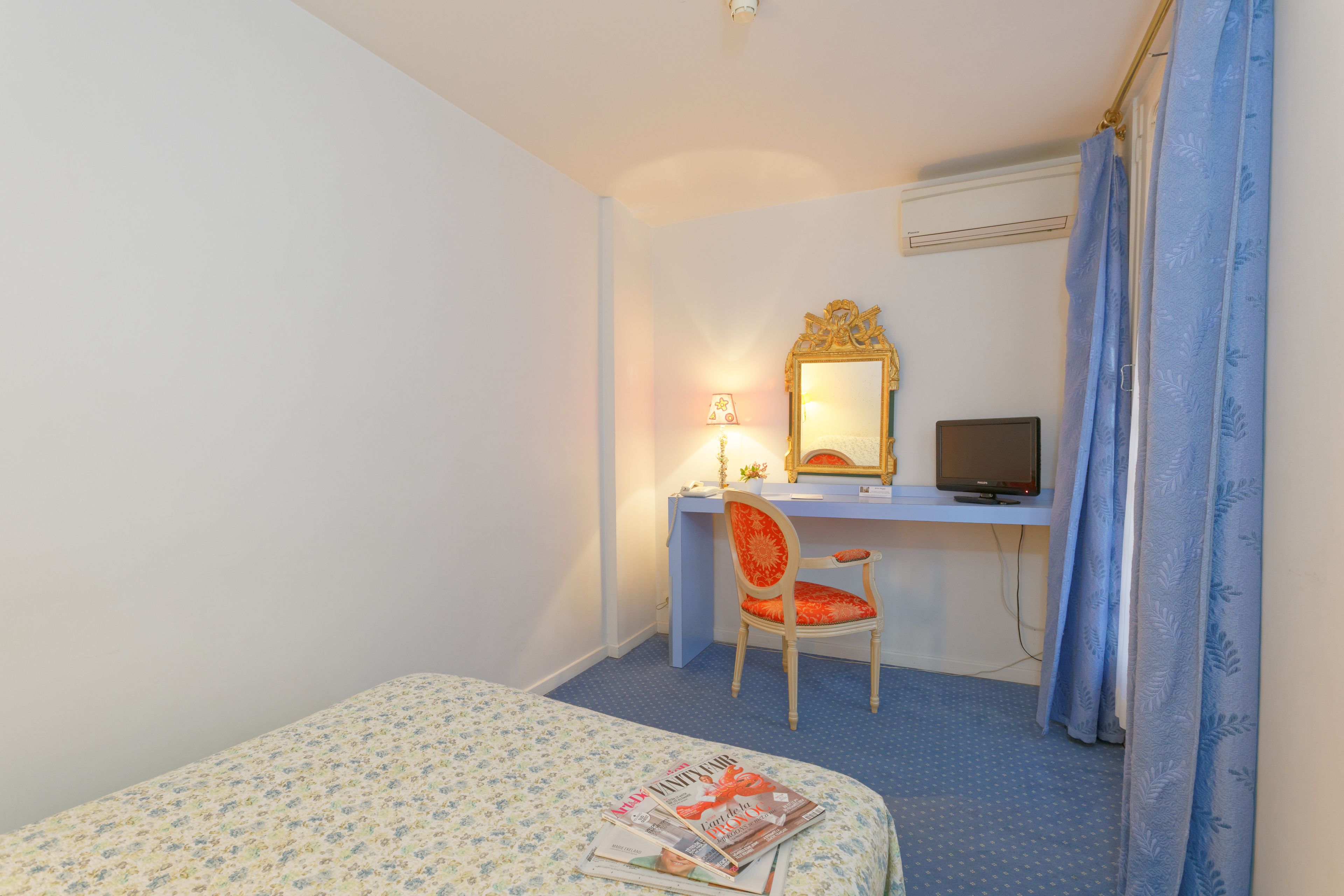 Un dormitorio con cama, escritorio con silla, televisor y espejo.