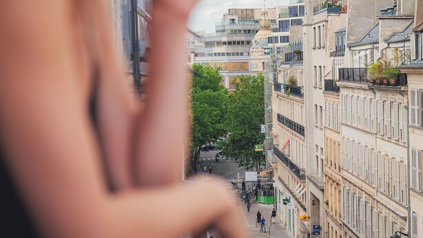 Una persona observa una calle urbana con edificios y vehículos.