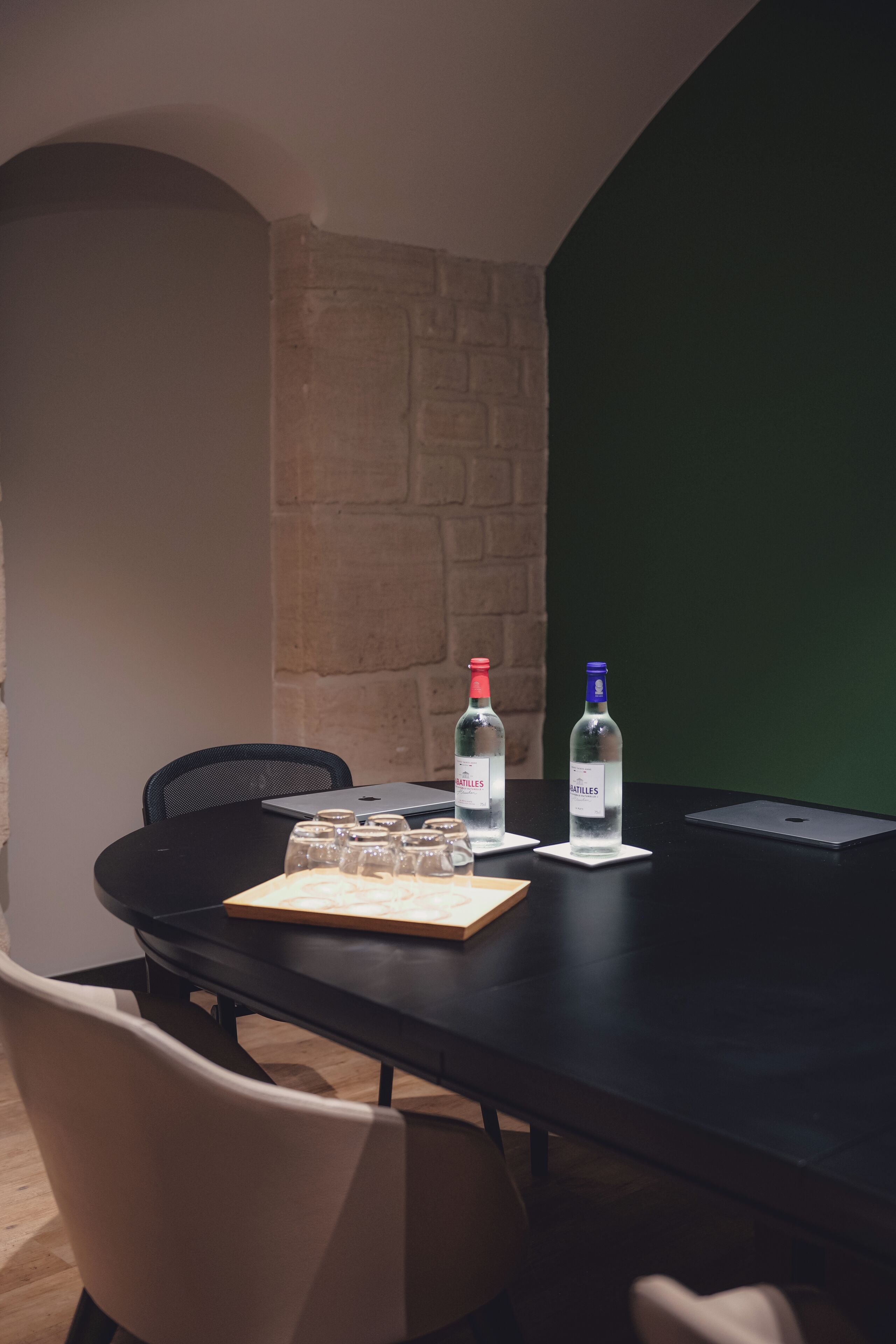 A conference table with two bottles of water, a laptop, and a notebook.