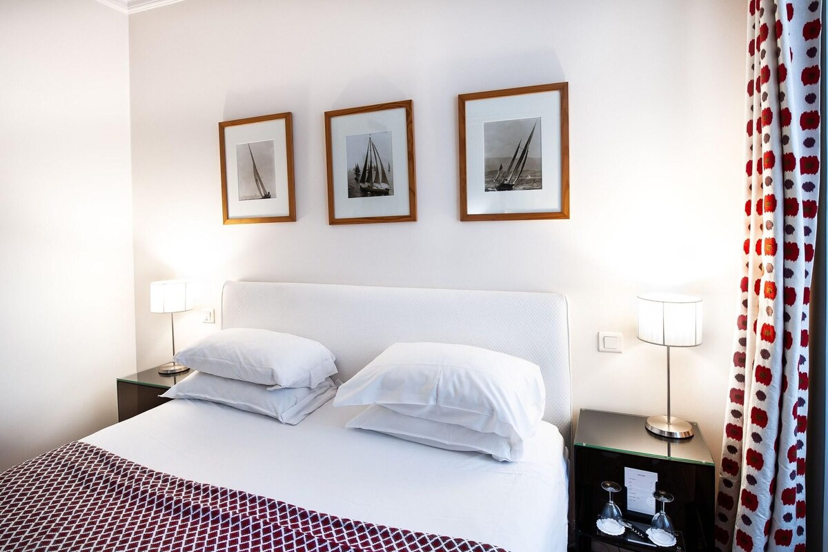 A hotel room with a bed, two bedside tables, and three framed pictures on the wall.