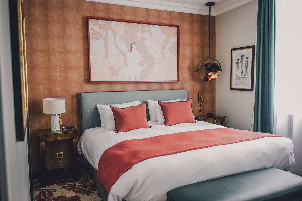 Habitación de hotel con una cama grande, una mesita de noche, una lámpara y un cuadro en la pared.