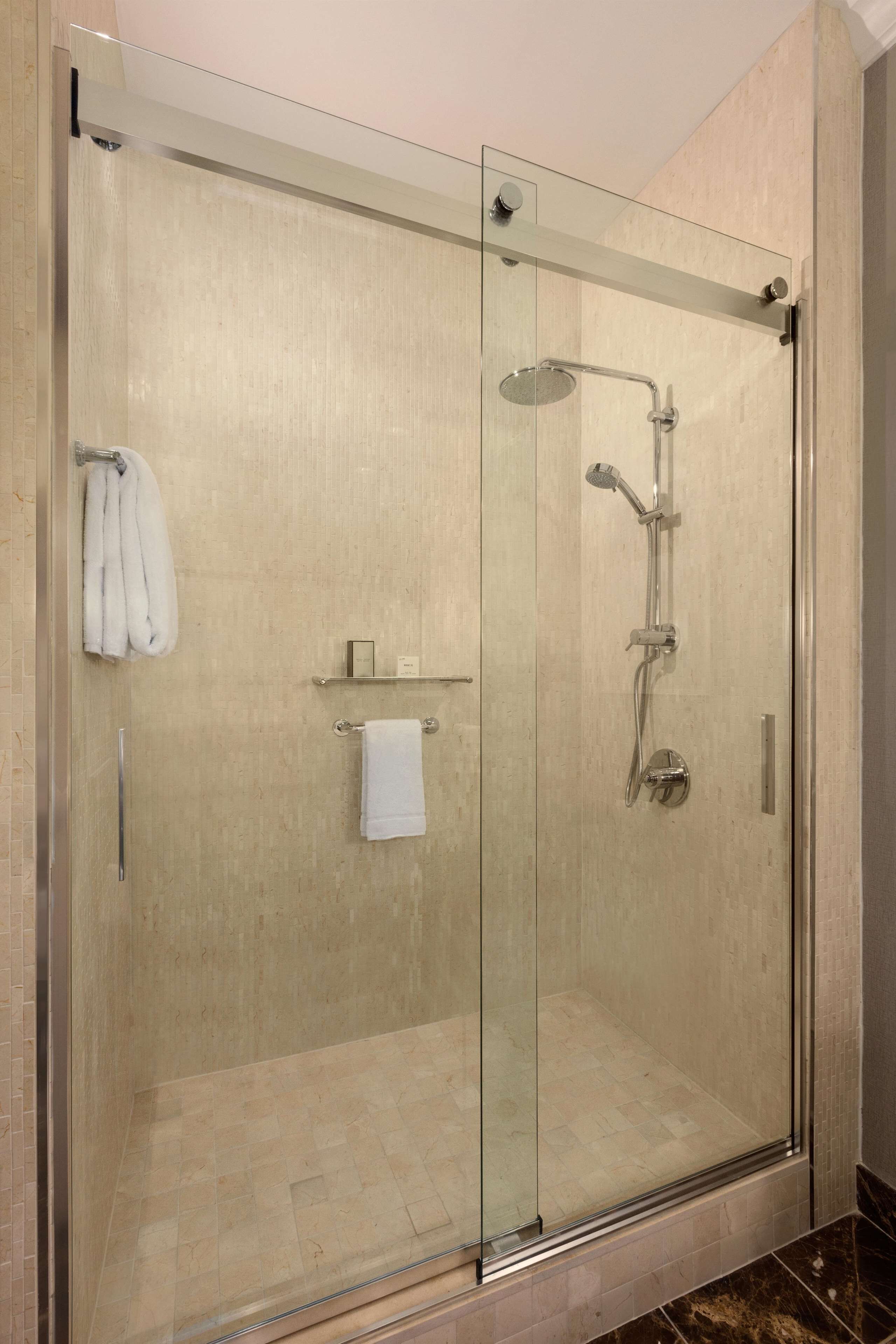 Une douche à l’italienne entièrementClose avec des parois en verre, dotée d’un pommeau de douche à main et d’un flexible de douche.
