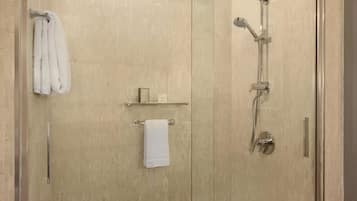 Una ducha a pie con mampara de vidrio y cabezal de ducha de mano.