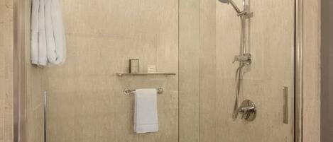 Une douche à l’italienne entièrementClose avec des parois en verre, dotée d’un pommeau de douche à main et d’un flexible de douche.