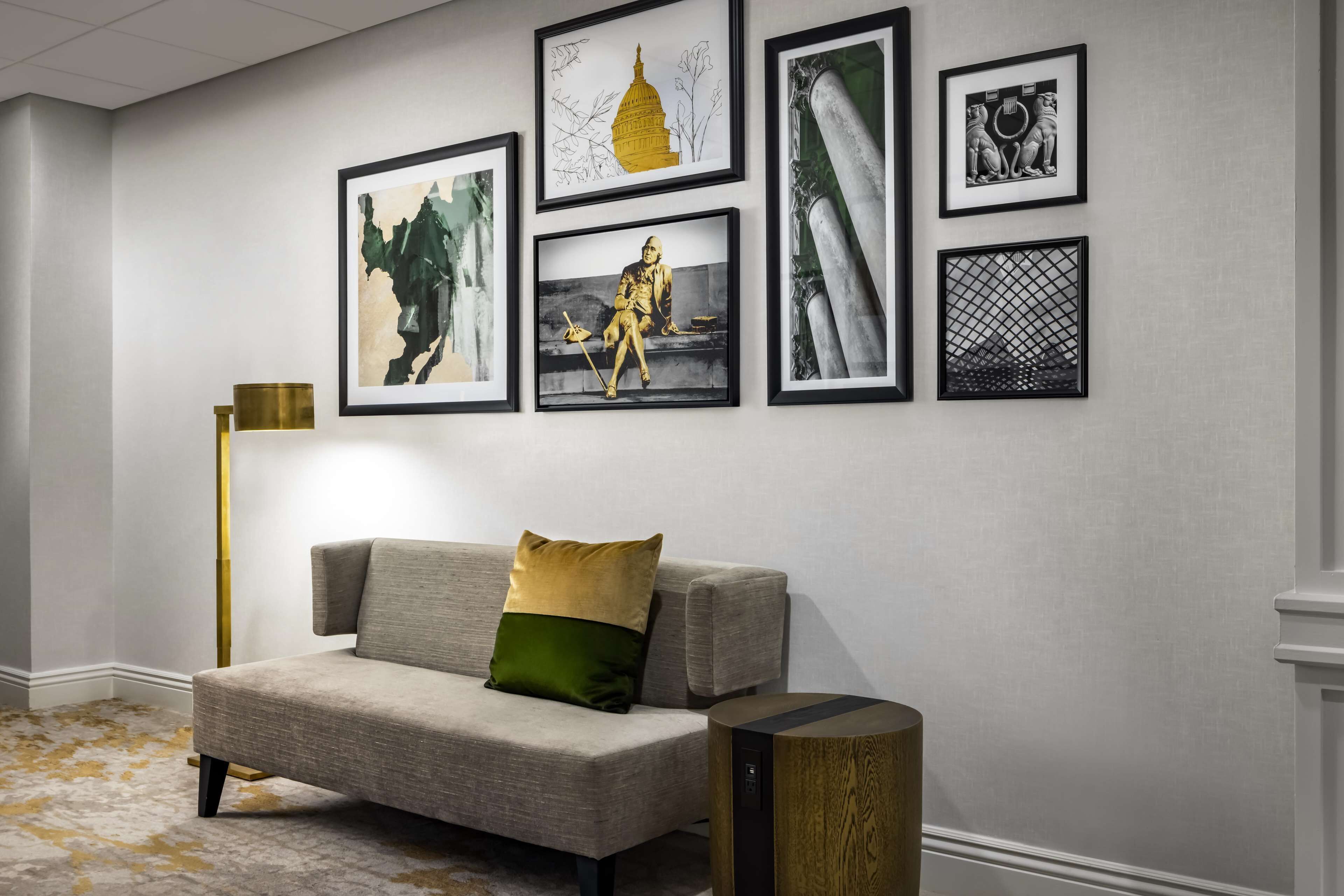 A modern living room with a sofa, a floor lamp, and framed artwork on the wall.