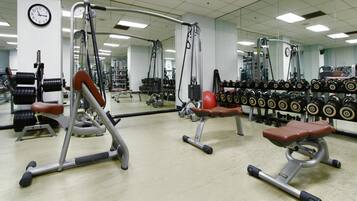 Une salle de sport équipée de divers appareils d’exercice, notamment des bancs et des haltères.