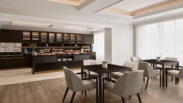 Una habitación de hotel moderna con una zona de bar, comedor y ventanas amplias.