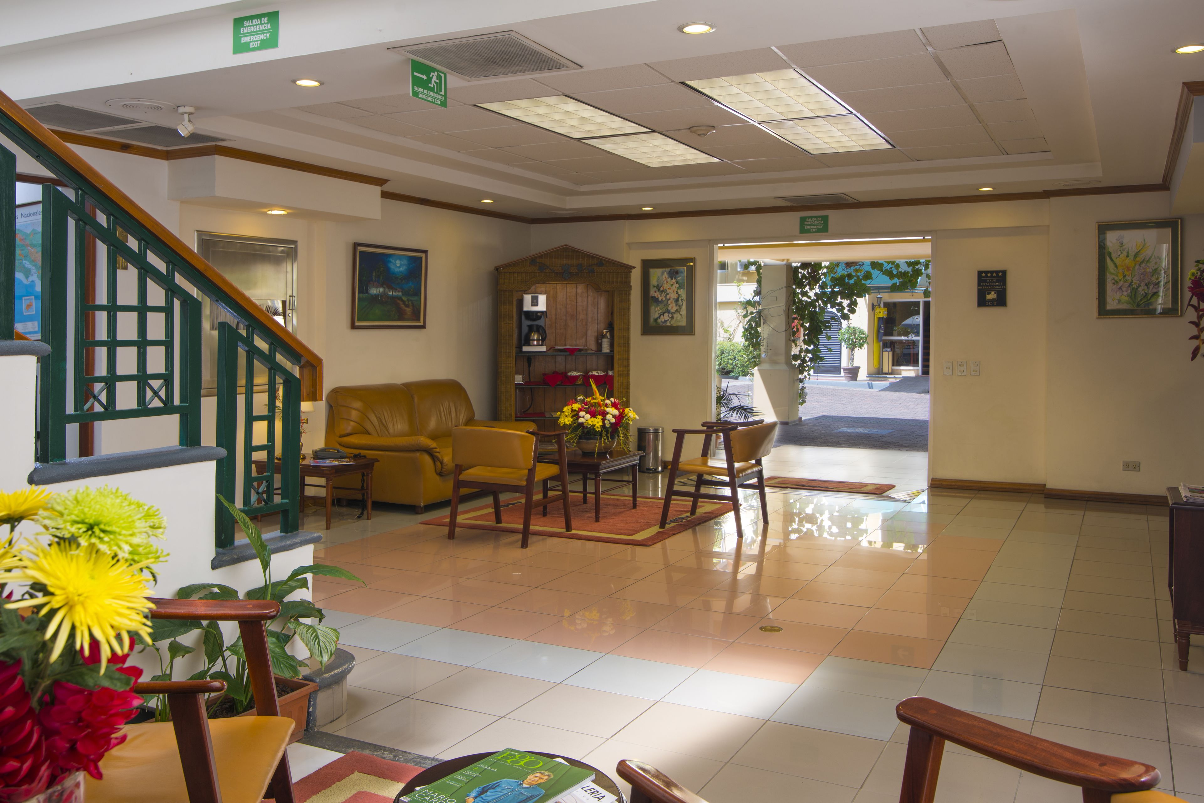 A lobby with a staircase, a reception desk, a yellow sofa, and a coffee machine.