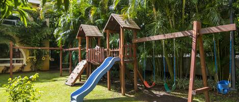Un parque infantil de madera con tobogán y columpios.