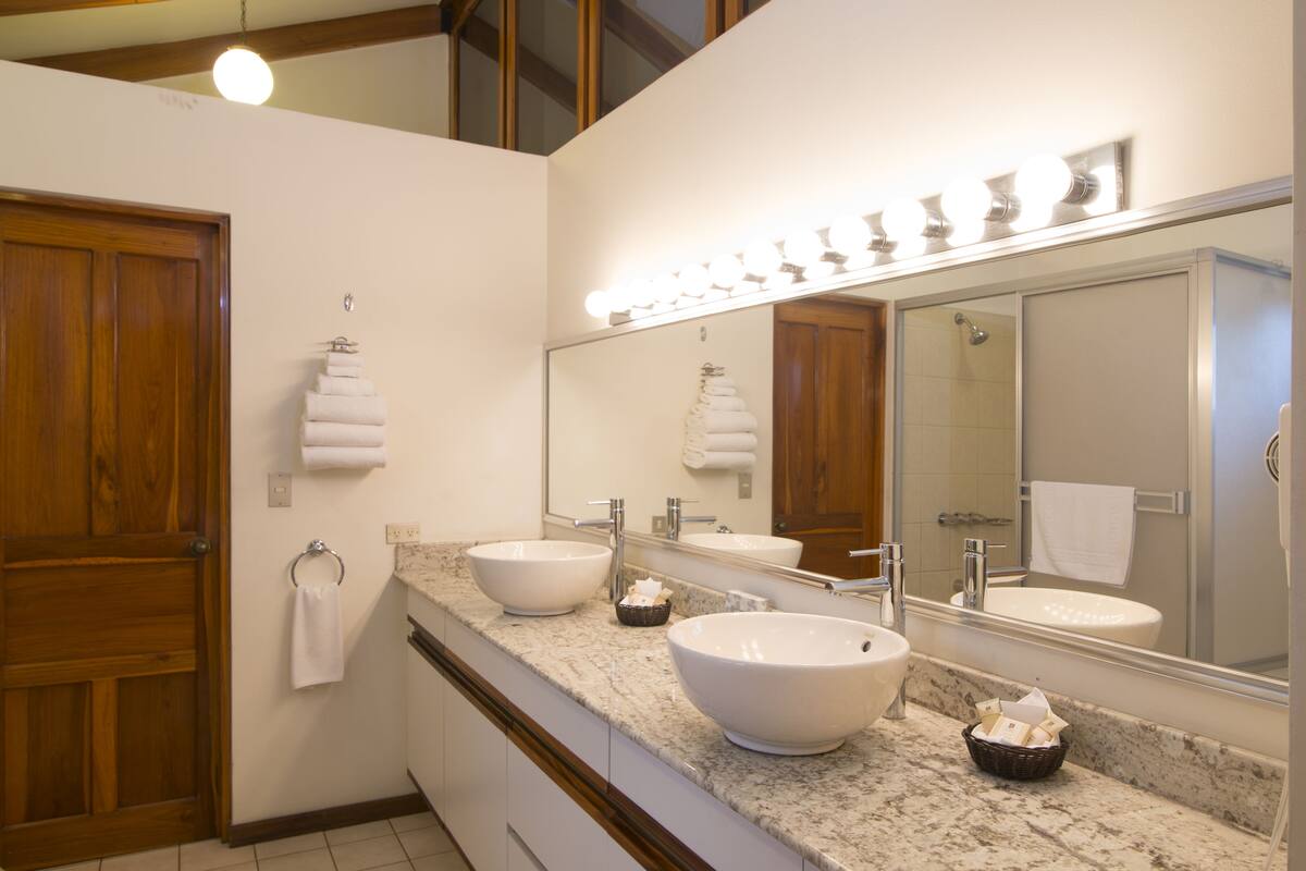 A bathroom with two large sinks, a vanity mirror, and a wooden door.