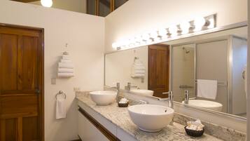 A bathroom with two large sinks, a vanity mirror, and a wooden door.
