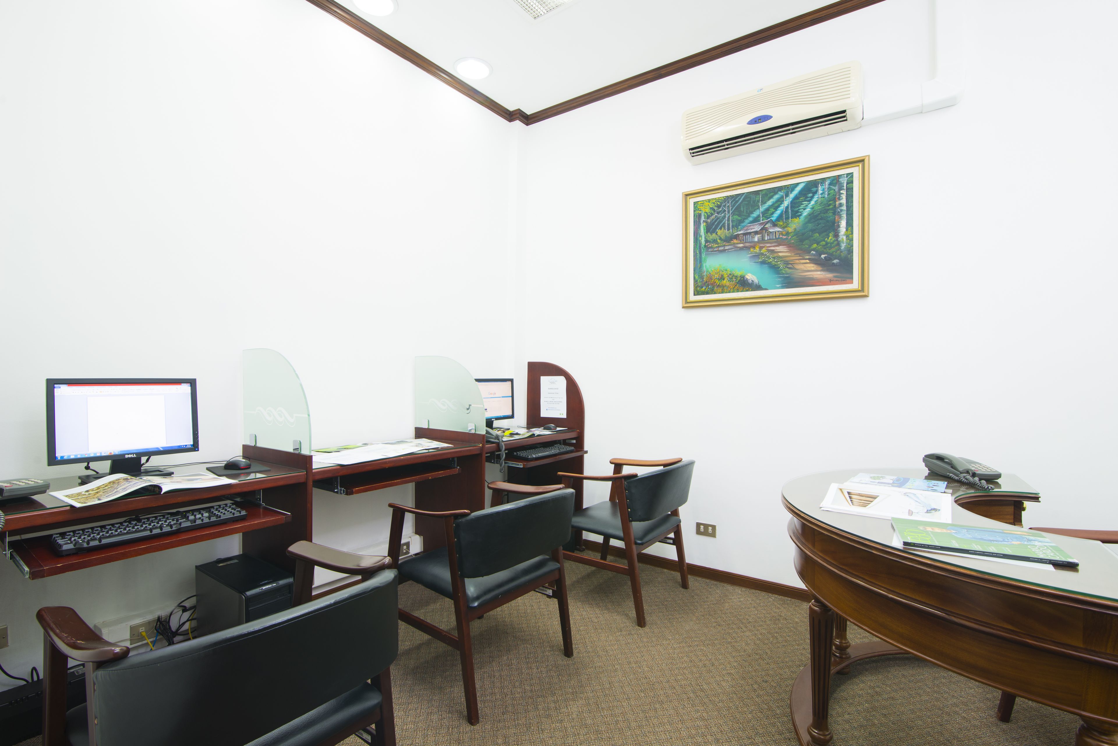 Une salle de conférence équipée d’un bureau, de chaises, d’un ordinateur et d’un tableau accroché au mur.
