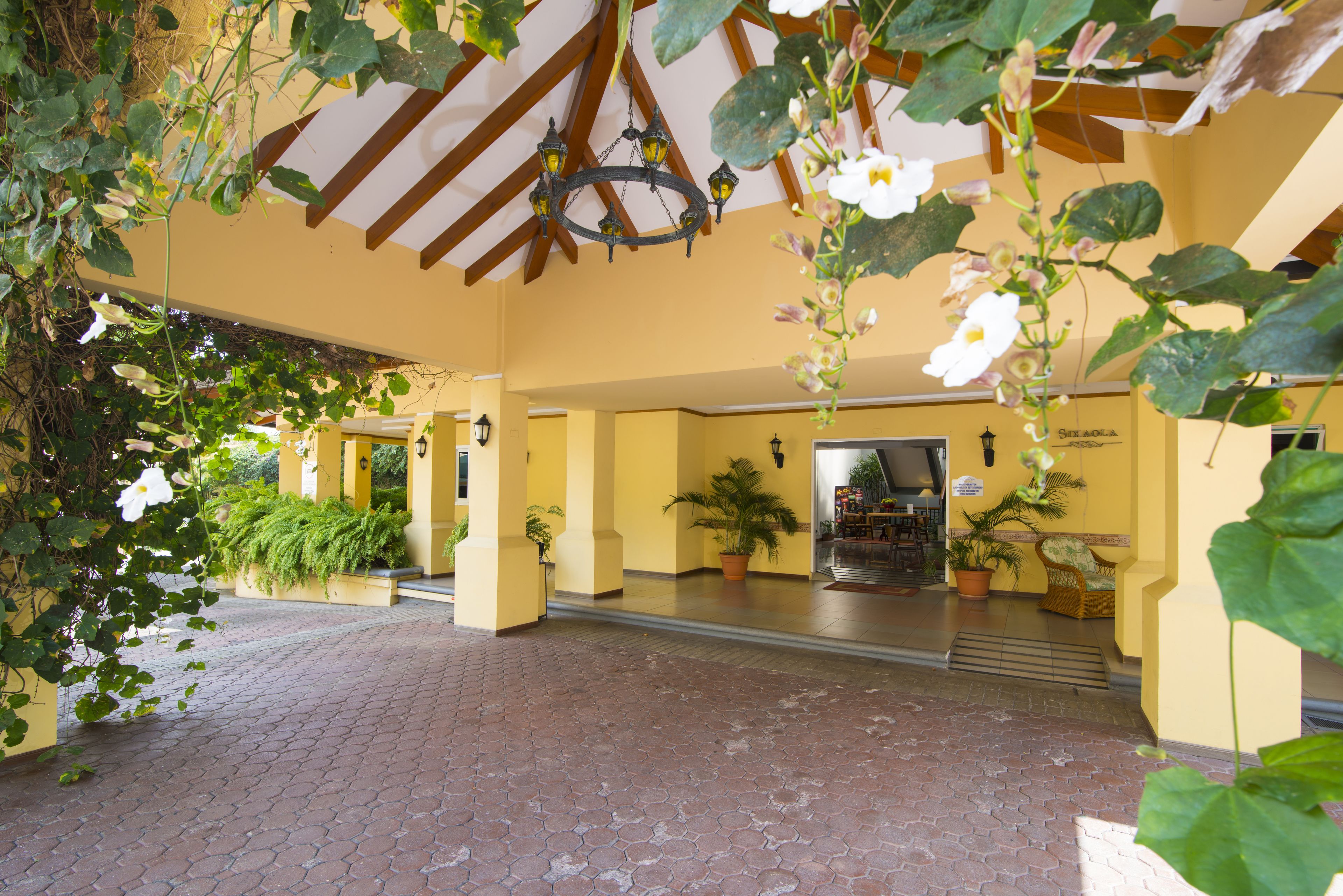 An indoor courtyard with a tiled floor, yellow walls, and potted plants.