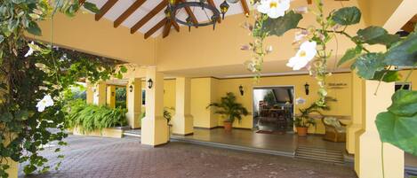 An indoor courtyard with a tiled floor, yellow walls, and potted plants.