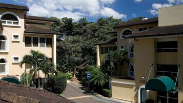 A residential street with houses, palm trees, and a clear sky.