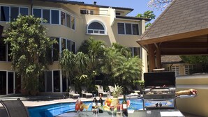 A pool area with lounge chairs, a barbecue grill, and a table with drinks and fruits. - Apartotel & Suites Villas del Rio (San Rafael)