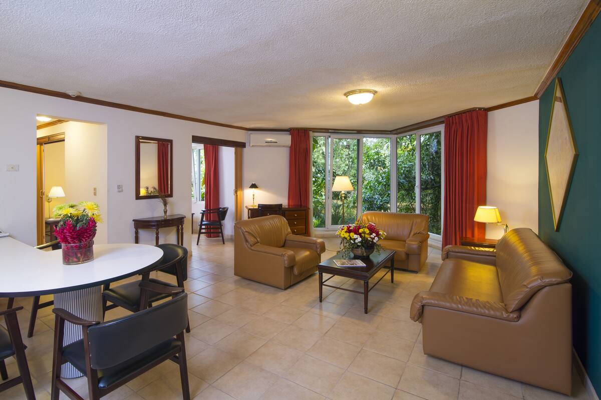 A living room with a dining area, featuring a sofa, chairs, a coffee table, and a dining table.