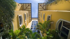A symmetrical building with a central atrium, surrounded by palm trees and featuring large windows and balconies. - Apartotel & Suites Villas del Rio (San Rafael)