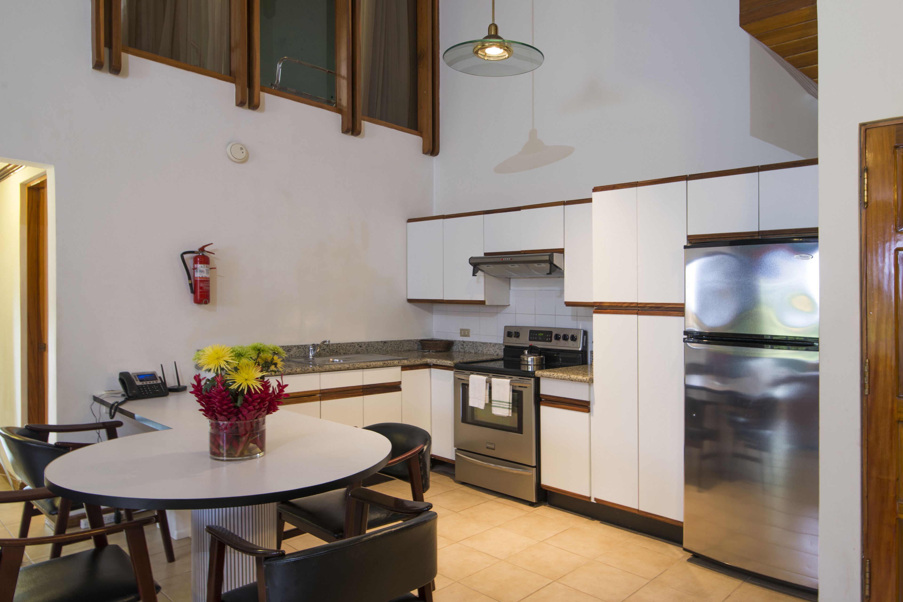 A modern kitchen with white cabinets, stainless steel appliances, and a round dining table with chairs.