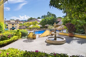 A courtyard with a swimming pool, a fountain, and various plants. - Apartotel & Suites Villas del Rio (San Rafael)