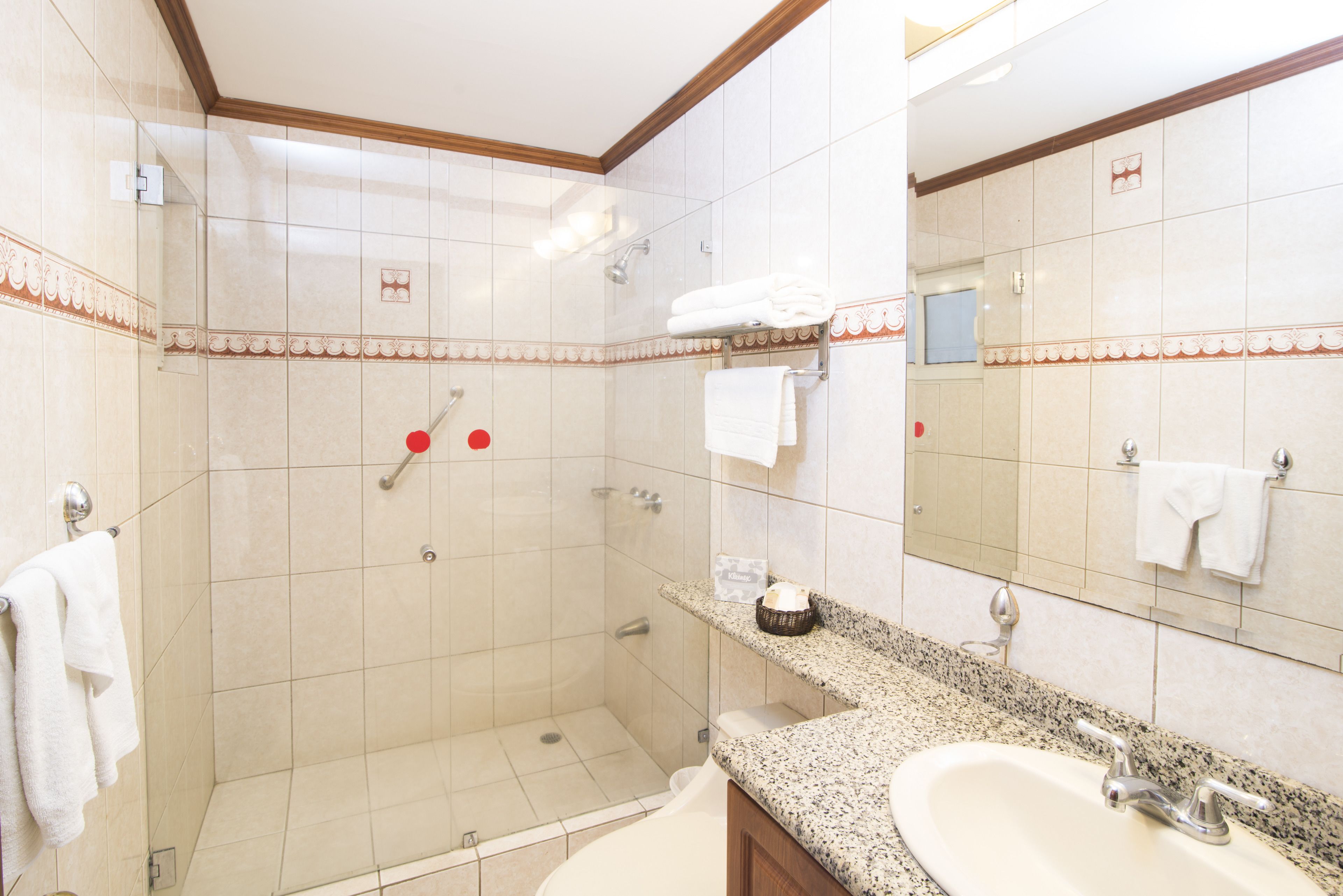 A hotel bathroom with a shower, a sink, and a mirror.