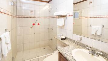 A hotel bathroom with a shower, a sink, and a mirror.
