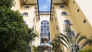 A building with a central fountain, surrounded by palm trees and a well-maintained garden. - Apartotel & Suites Villas del Rio (San Rafael)