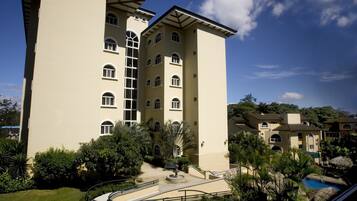 A multi-story hotel with a central courtyard, a swimming pool, and lush greenery.