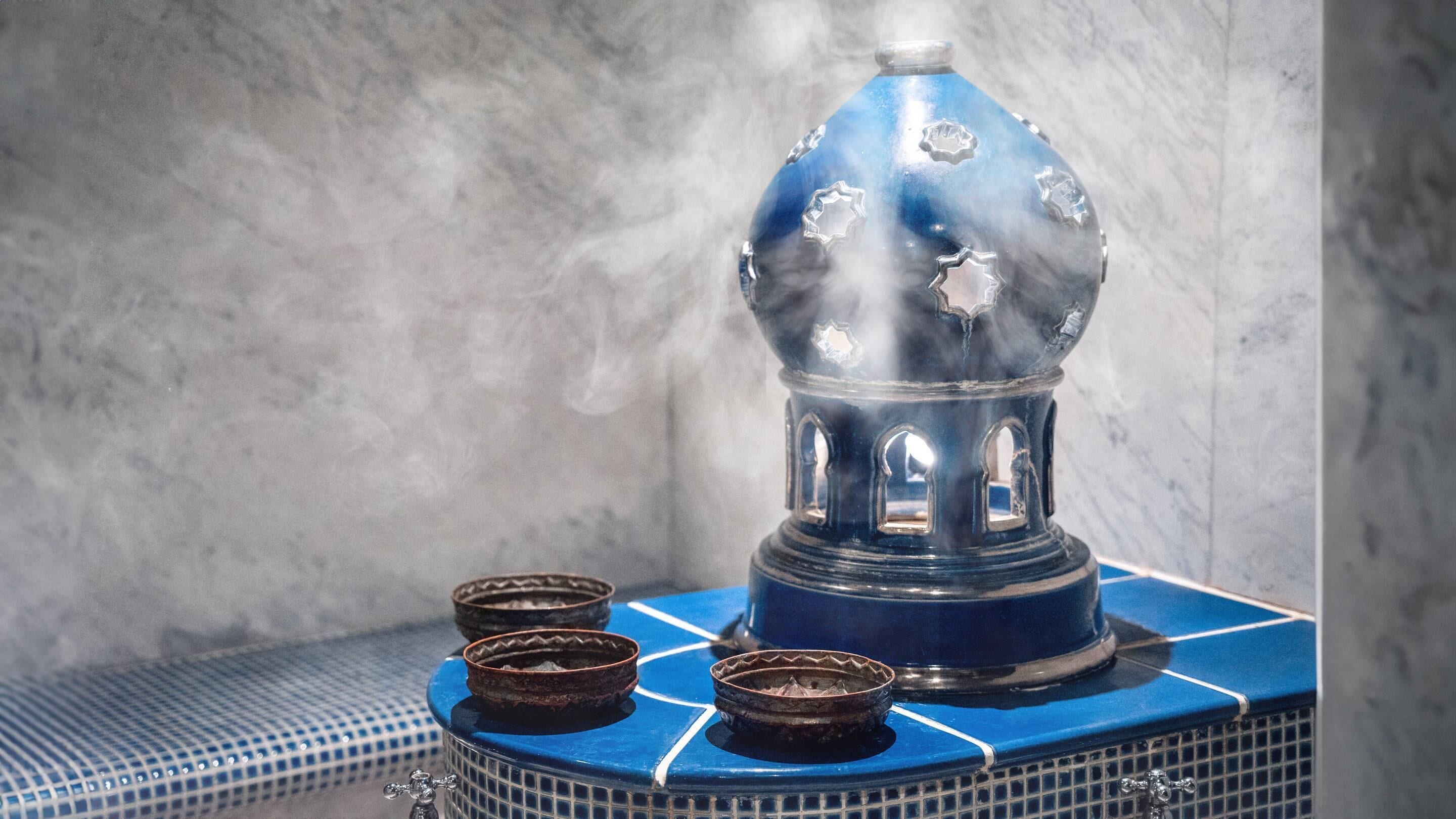 Un objet décoratif bleu et blanc, surmonté d’un dôme et agrémenté de quatre petits bols, posé sur une surface à motifs.