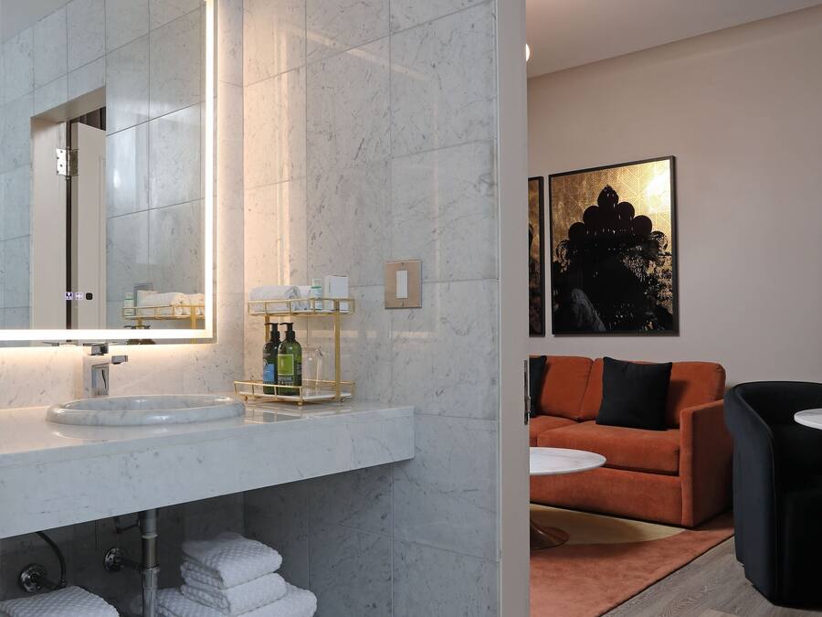 Un baño moderno con lavamanos de mármol, un espejo grande y un perchero para toallas.