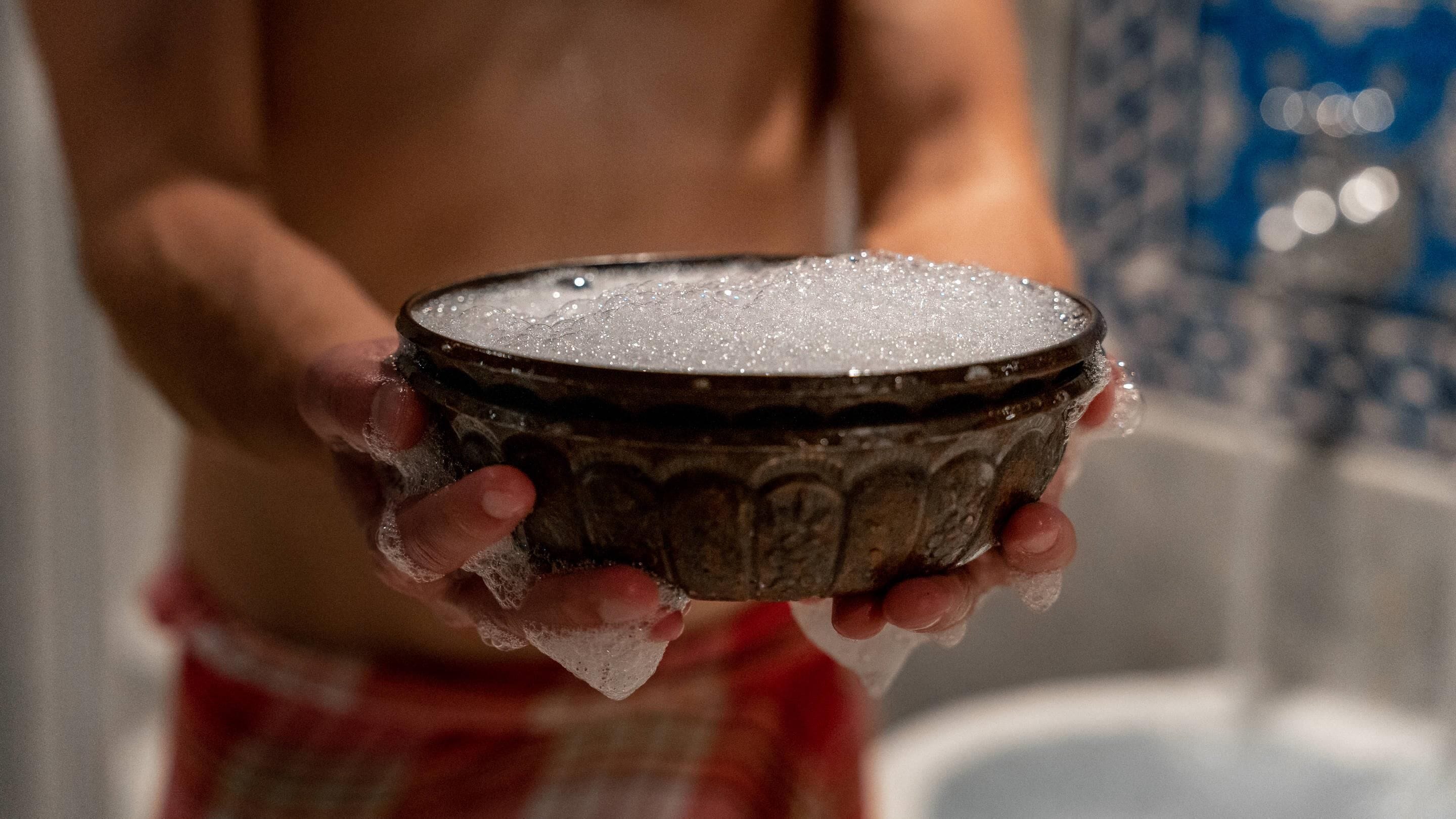 A person holding a bowl with a textured surface, possibly containing a food item.