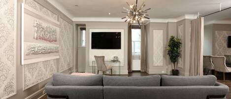 A modern living room with a grey sofa, a glass coffee table, and a chandelier.