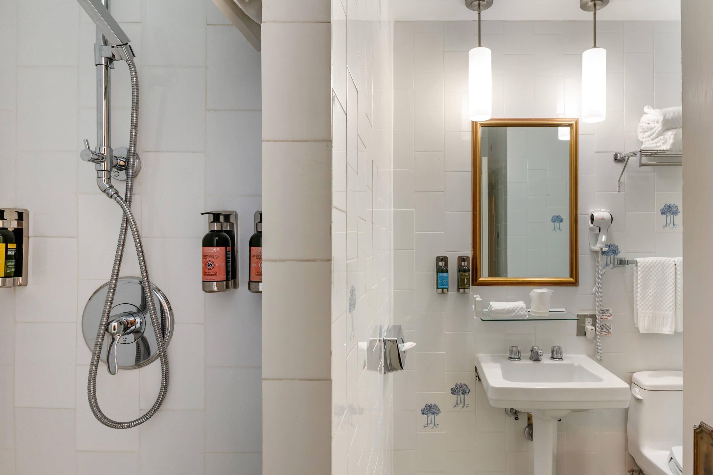 Un baño con ducha, lavamanos, espejo y toallero.