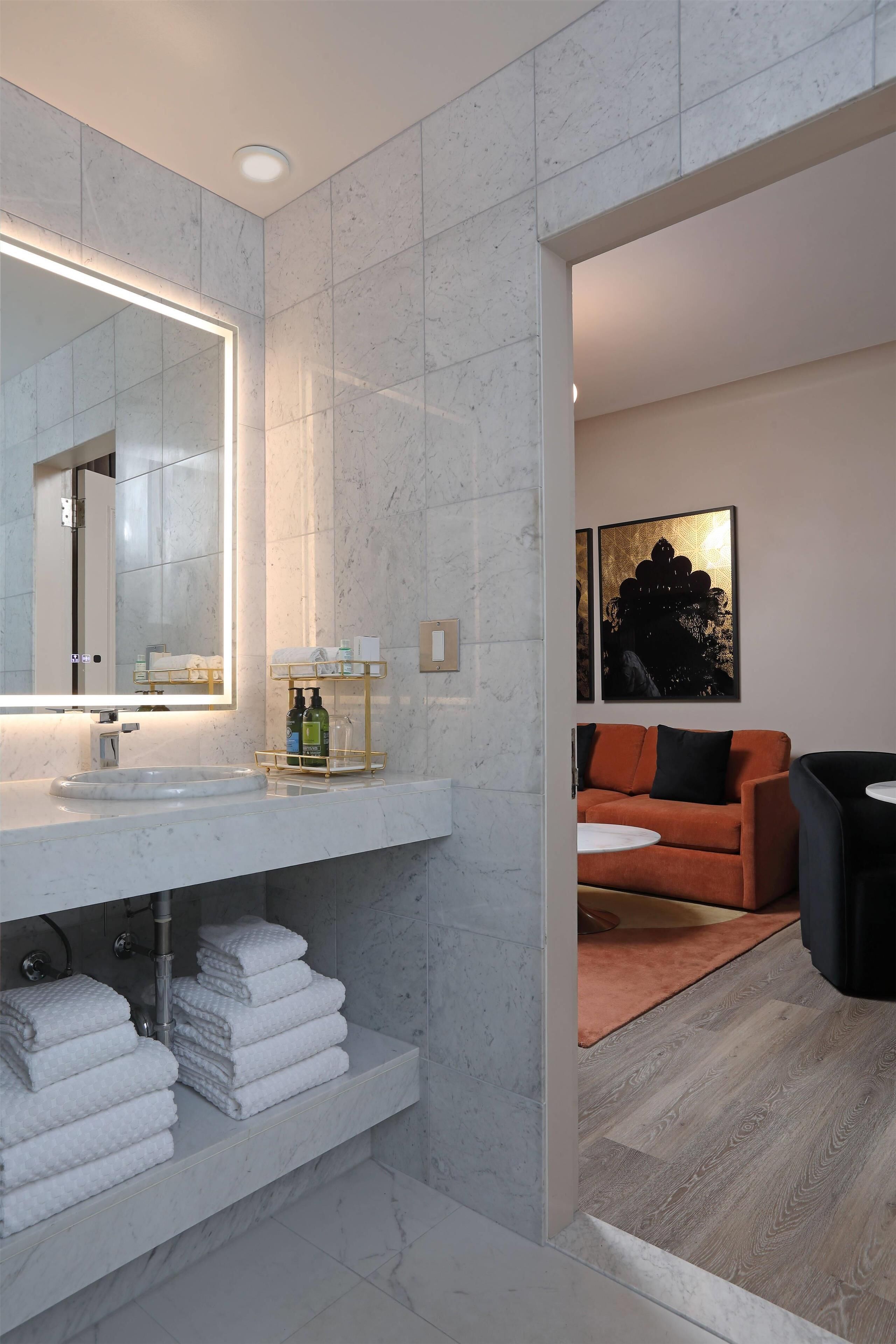 A modern bathroom with a marble vanity, a large mirror, and a towel rack.