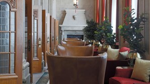 A grand lobby with high ceilings, a fireplace, leather armchairs, and a large wooden door. - The Fort Garry Hotel, Spa and Conference Centre, an Ascend Collection Hotel (Winnipeg)