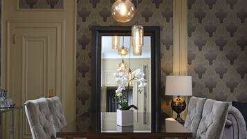 A dining area with a wooden table, two upholstered chairs, and pendant lighting.