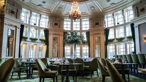 A grand dining room with ornate chandeliers, large windows, and lush green plants. - The Fort Garry Hotel, Spa and Conference Centre, an Ascend Collection Hotel (Winnipeg)