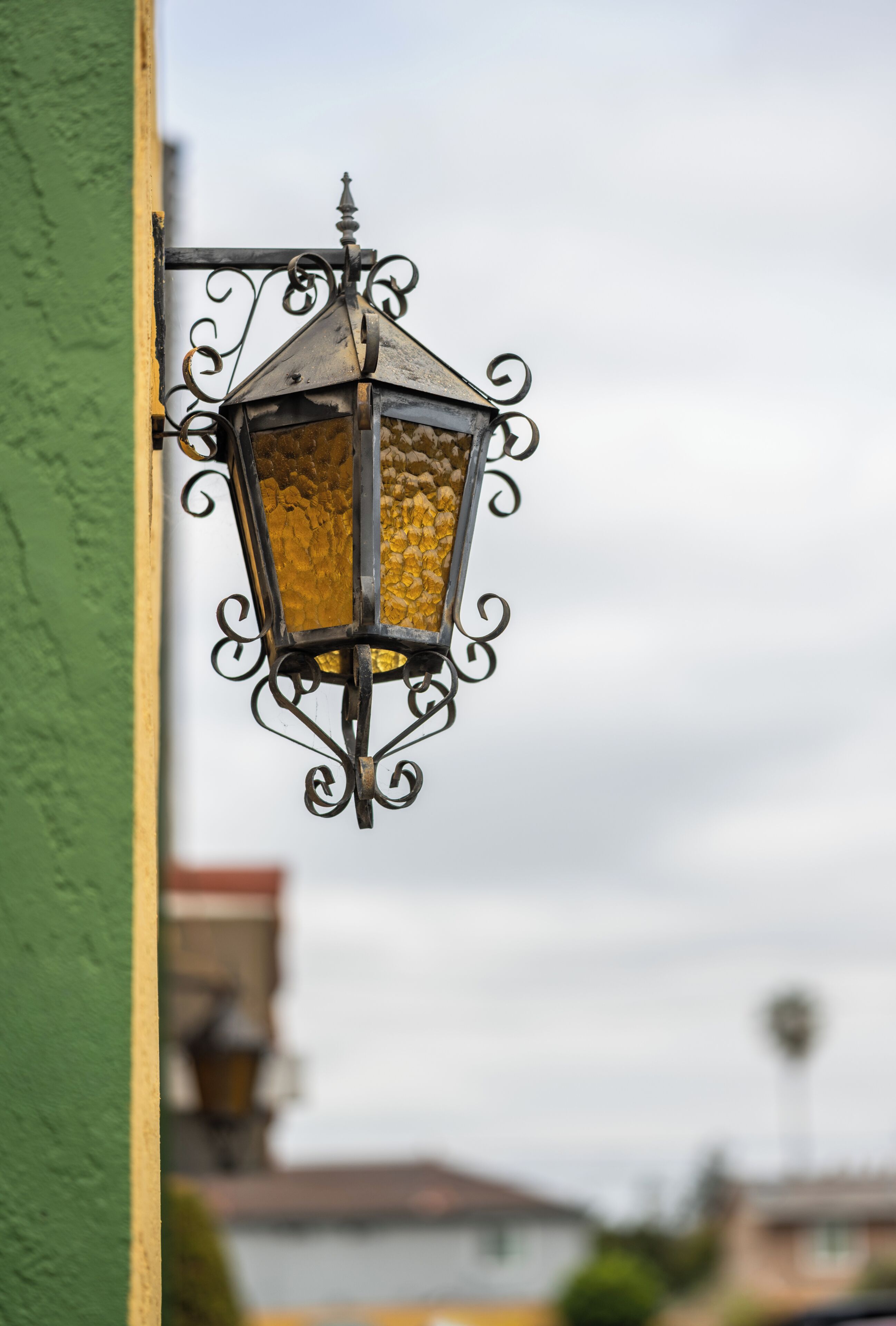Gros plan d’une lanterne décorative en métal, dotée d’un abat-jour en verre texturé, fixée à un mur.