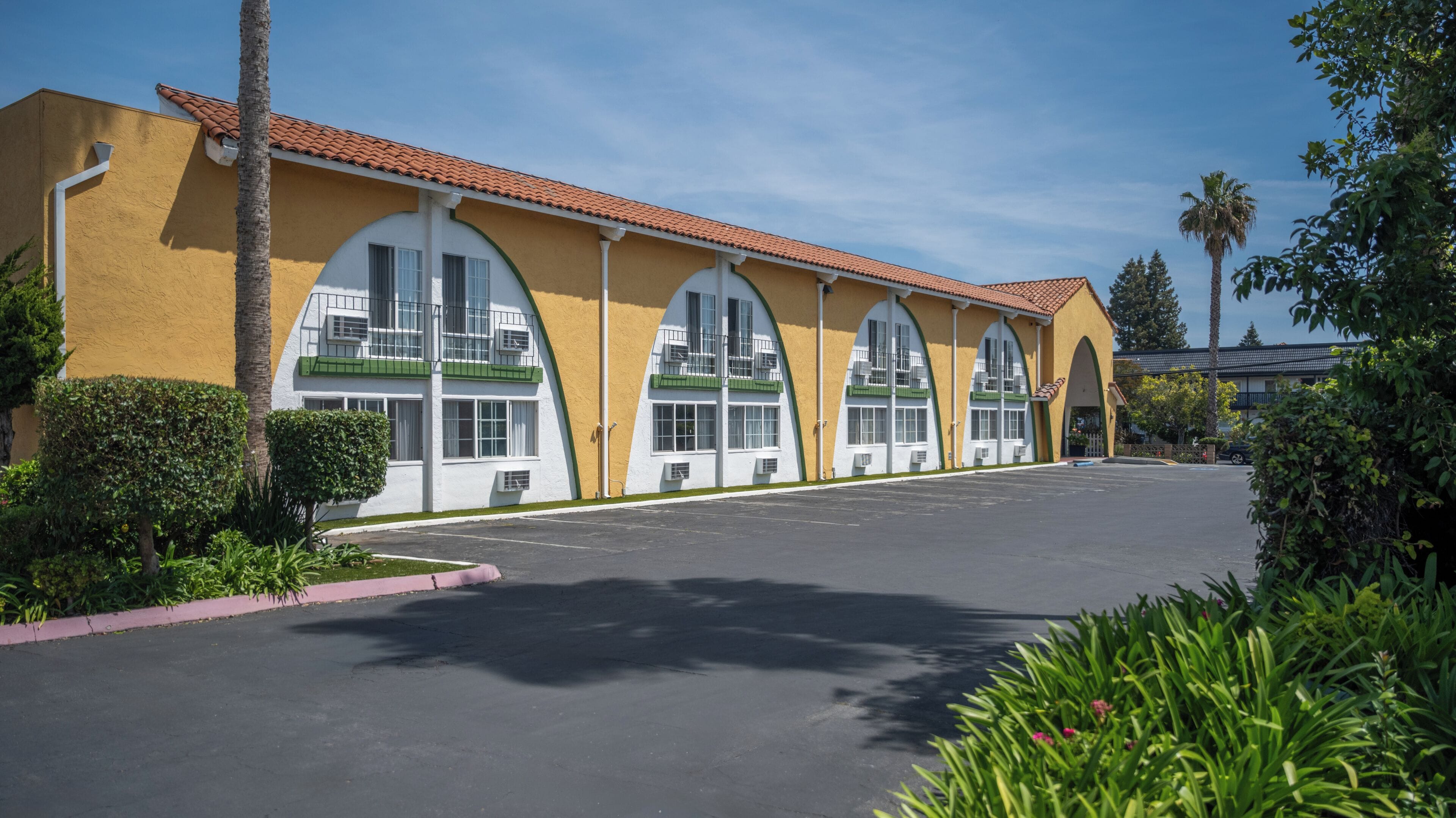 A building with a yellow facade, large arched windows, and a parking lot.