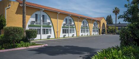 A building with a yellow facade, large arched windows, and a parking lot.