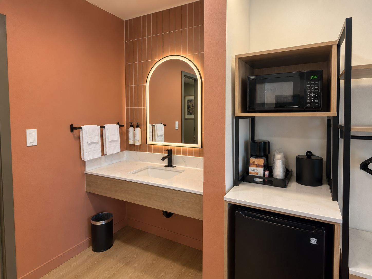 Une salle de bain moderne avec un lavabo, un miroir et un four à micro-ondes placé au-dessus.