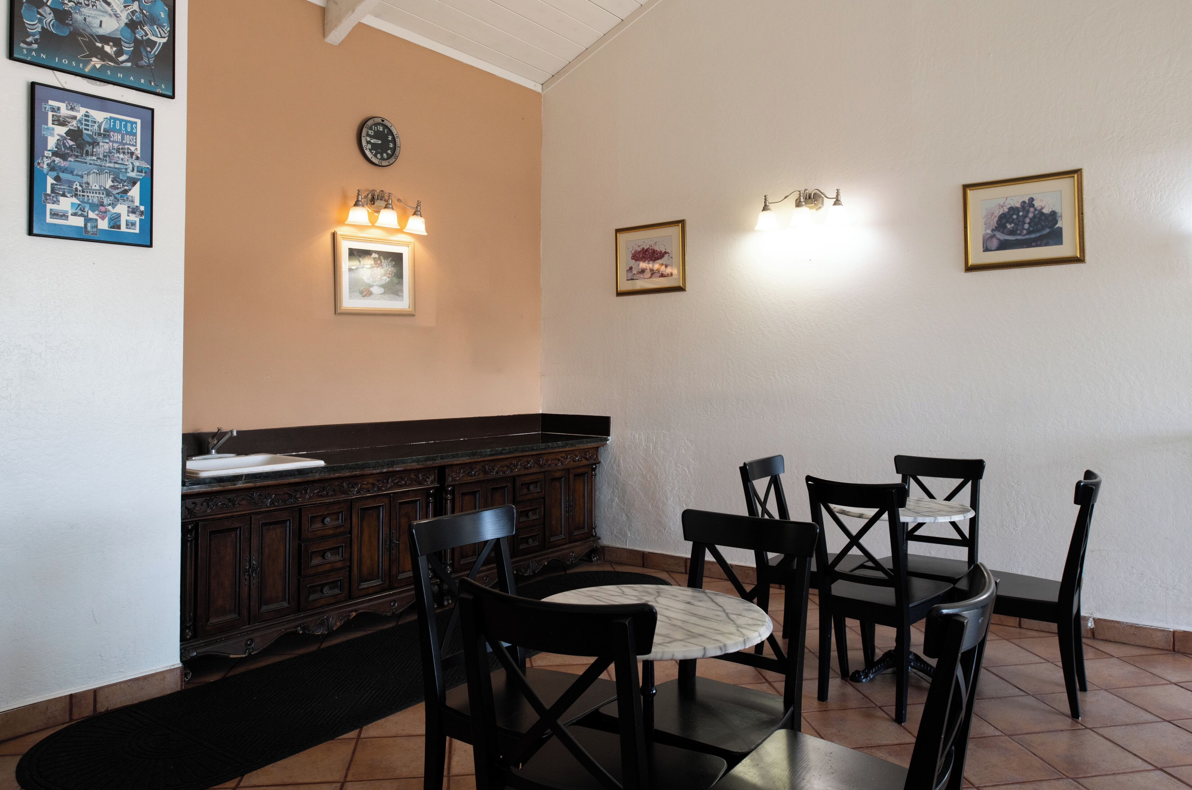 Un coin repas comprenant une table ronde, quatre chaises, un bar en bois foncé et des luminaires fixés au mur.