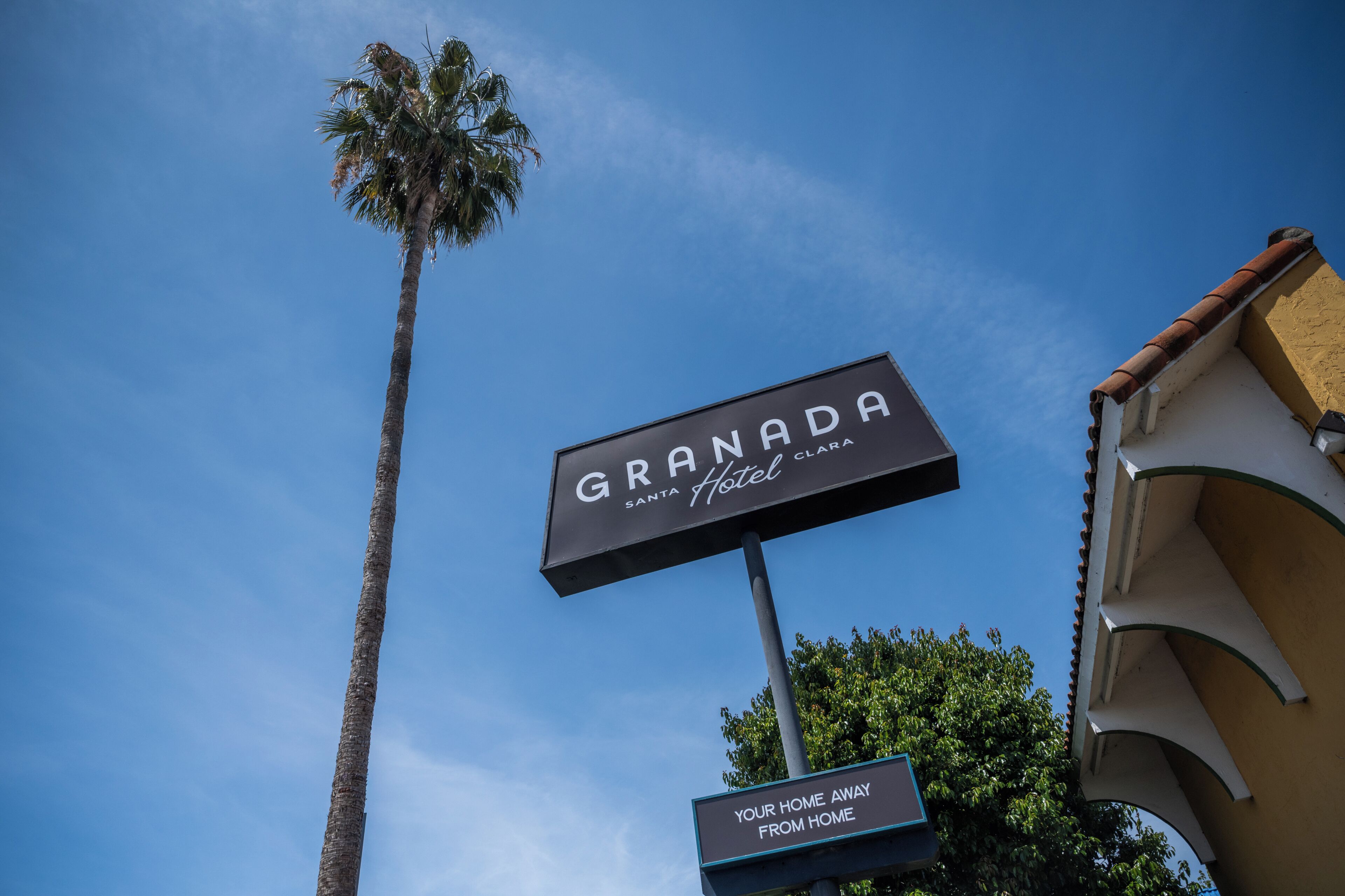 A hotel sign with 'GRANADA Santa Clara Hotel' and a smaller sign below stating 'YOUR HOME AWAY FROM HOME.'