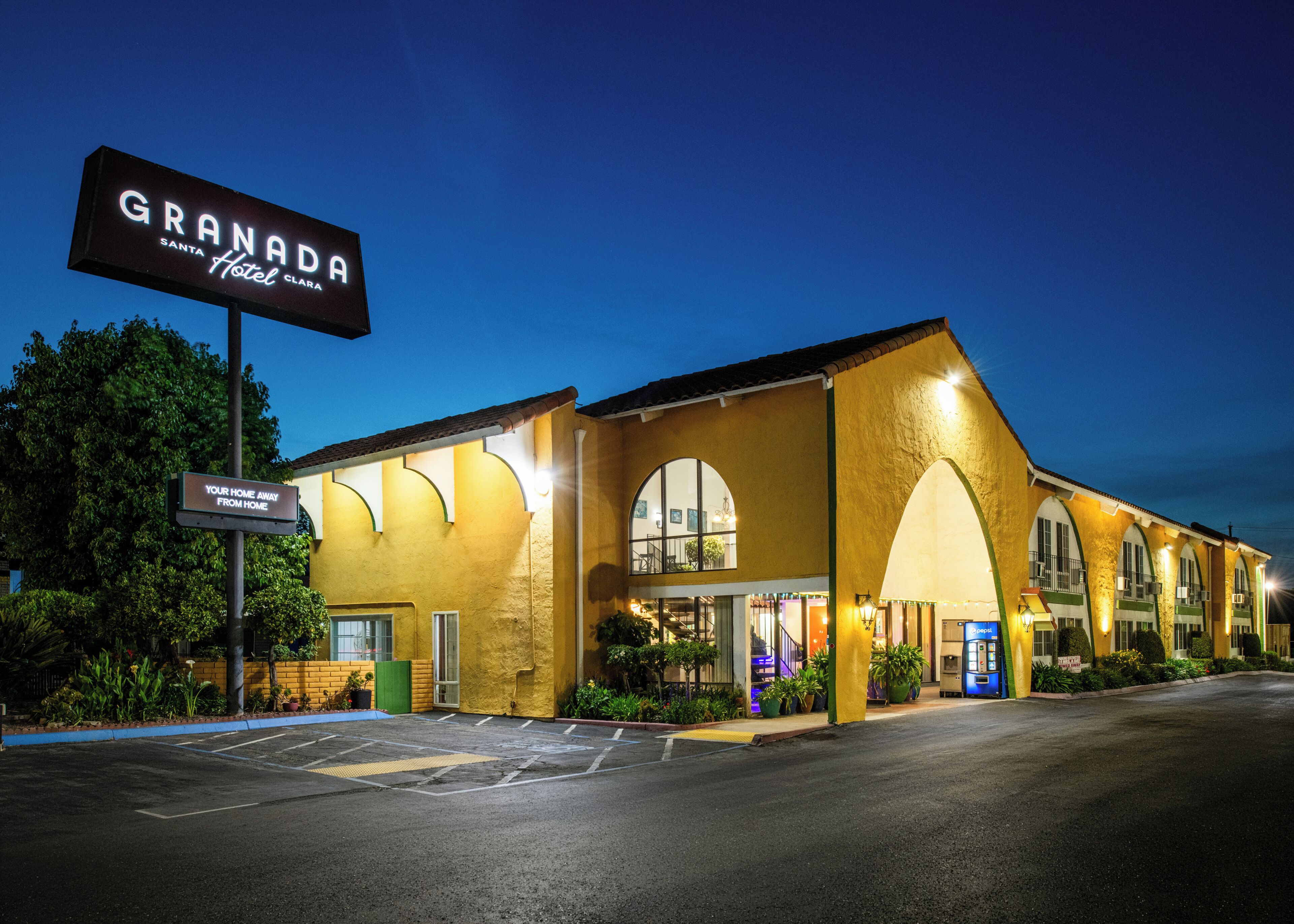 A hotel with a large sign reading 'GRANADA Santa Clara Hotel' and a sign below stating 'YOUR HOME AWAY FROM HOME.'