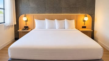 A hotel room with a large bed, two bedside tables, a headboard with a geometric pattern, and two wall-mounted lamps.