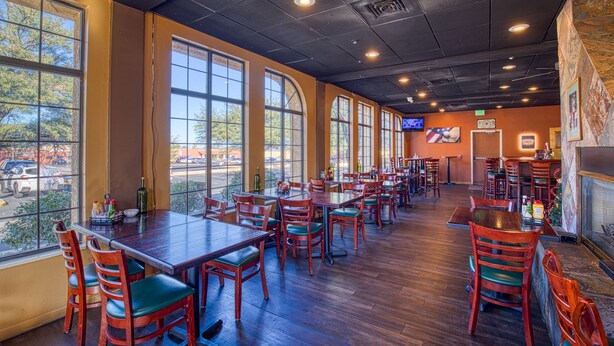 A restaurant with multiple tables and chairs, large windows, and a fireplace. - Best Western Green Valley Inn (Green Valley)
