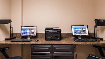 A workspace with two monitors, a printer, and a keyboard on a granite countertop.